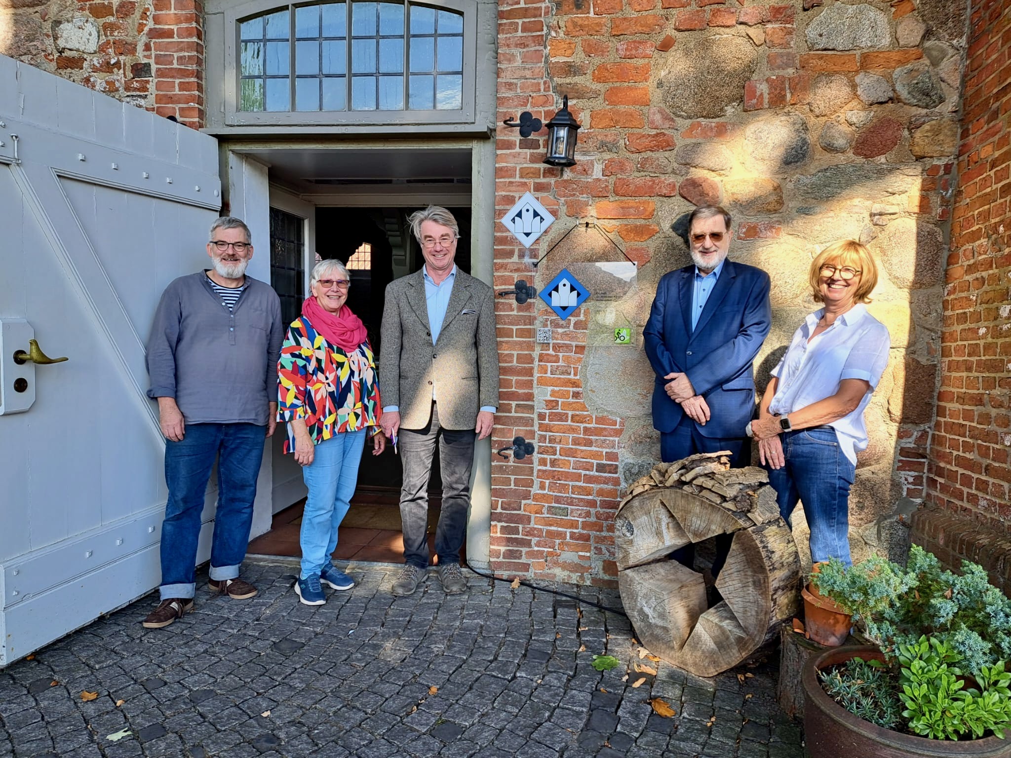 vlnr: Diakon Holger Kuk, Kirchenvorstandsvorsitzende Brigitte Bretschneider, Dr. Wolfgang Rüther, Referent für „Kirche in Freizeit und Tourismus“ der Ev.-Luth. Landeskirche Hannovers, Jürgen Böhme, scheidender Hollenstedter Bürgermeister und Kirchenvorstandsvorsitzende Heike Christiansen vor dem Signet der Radwegekirche. Foto: A. Heins